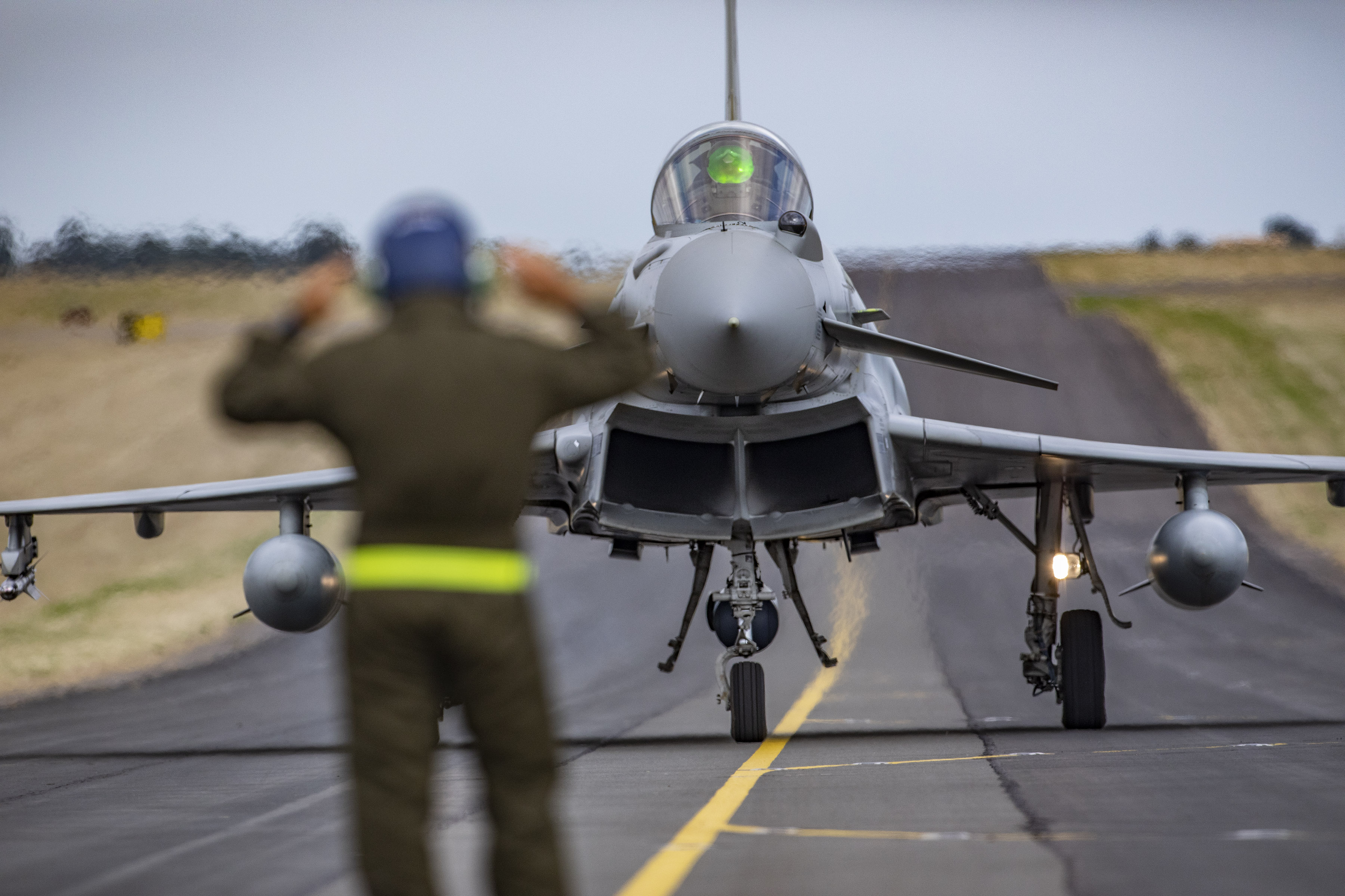 Image shows RAF aviators guiding aircraft on the runway.